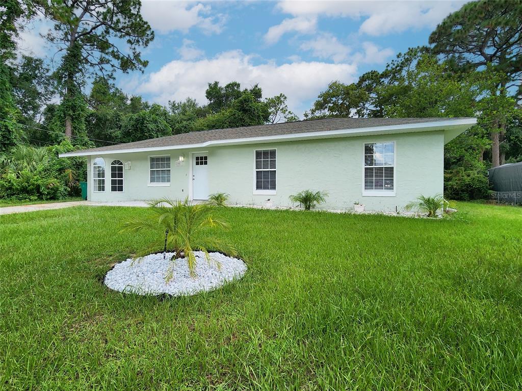 A light green, single-story house with a white front door and a grassy front yard — 1001 JONES AVENUE, INVERNESS, FL