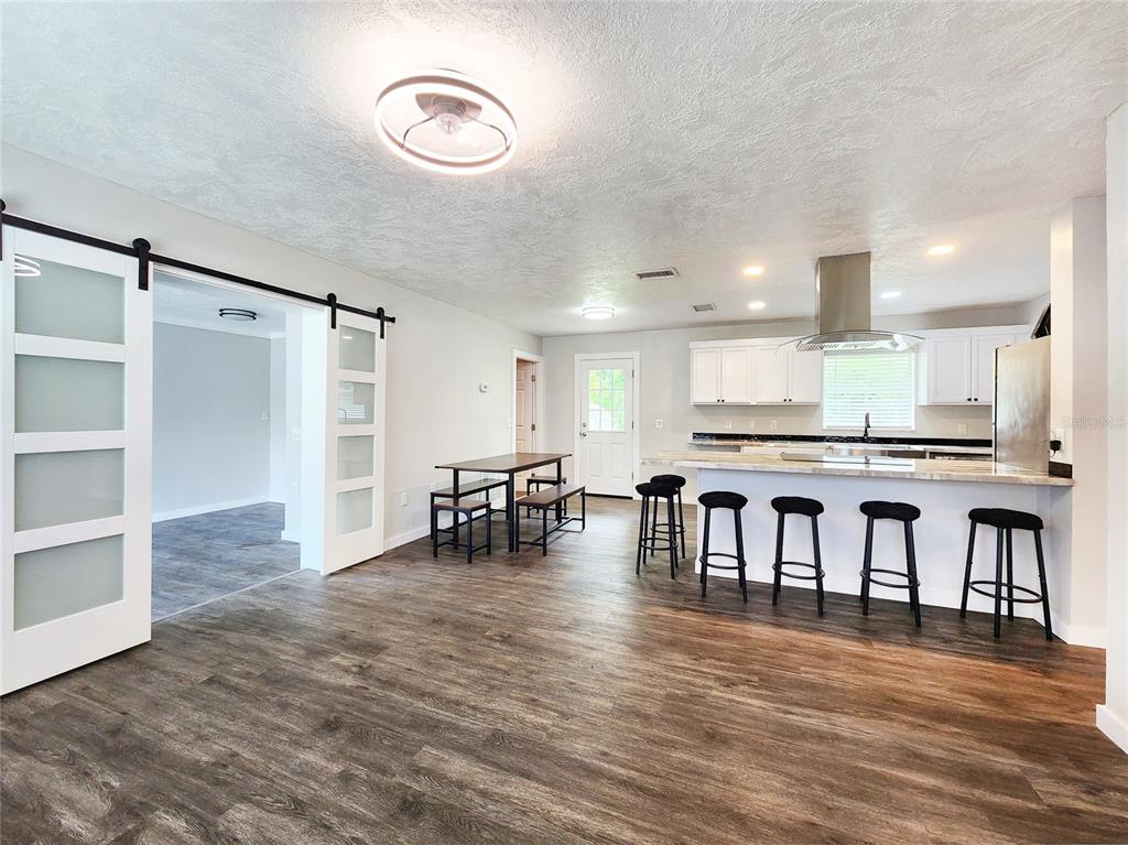 An open-concept kitchen and dining area features white cabinets, a breakfast bar, and wood flooring — 1001 JONES AVENUE, INVERNESS, FL