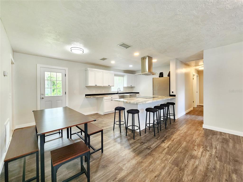 A kitchen and dining area with white cabinets, a kitchen island, and wood-look flooring — 1001 JONES AVENUE, INVERNESS, FL