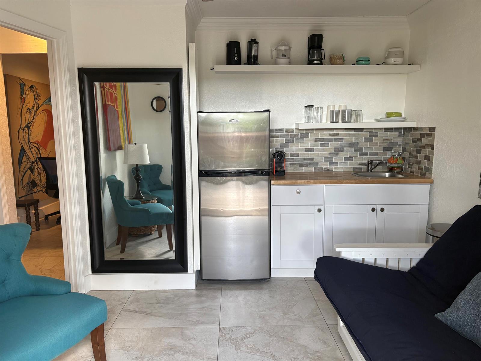 A kitchenette with stainless steel appliances, white cabinets, and open shelving next to a mirror — 2565 Meadow Road, West Palm Beach FL 33406, WEST PALM BEACH, FL