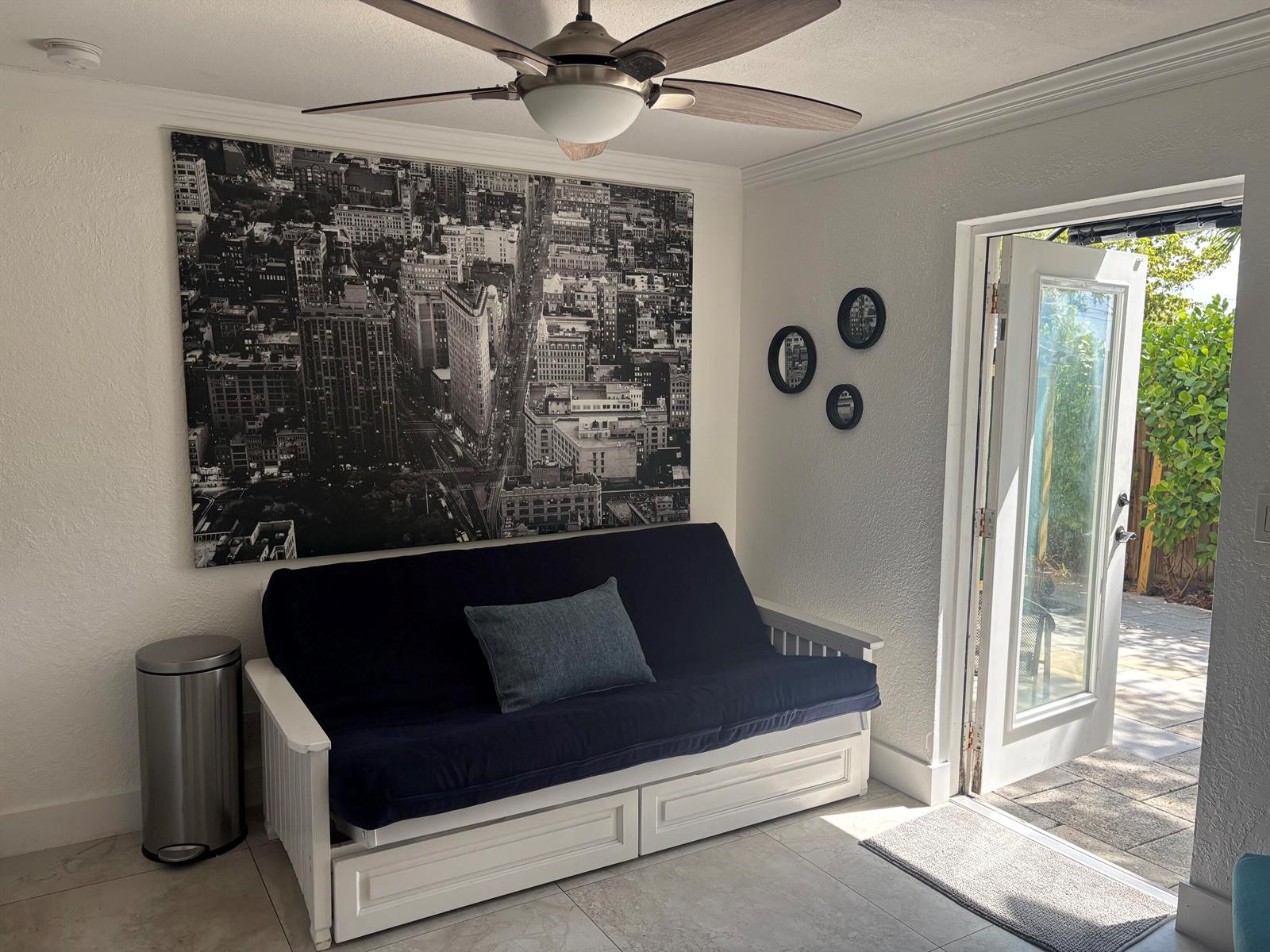 A room with a futon, a large city skyline wall art, and an open glass door — 2565 Meadow Road, West Palm Beach FL 33406, WEST PALM BEACH, FL