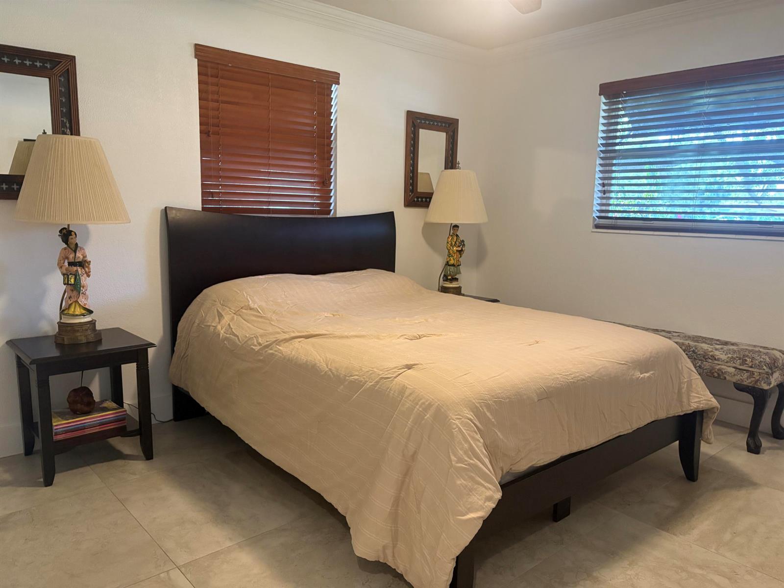 A bedroom features a dark wood bed frame, two matching nightstands with lamps, and tile flooring — 2565 Meadow Road, West Palm Beach FL 33406, WEST PALM BEACH, FL