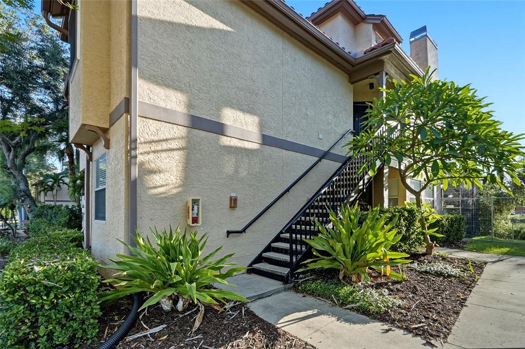 An exterior view of a multi-story building with a staircase leading to an upper entrance — 2400 FEATHER SOUND DRIVE UNIT 1428, CLEARWATER, FL