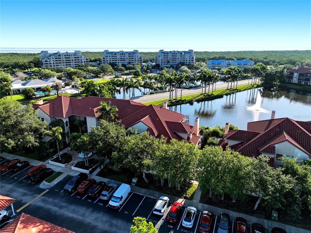 An aerial view shows multi-story residential buildings with red tile roofs near a lake — 2400 FEATHER SOUND DRIVE UNIT 1428, CLEARWATER, FL