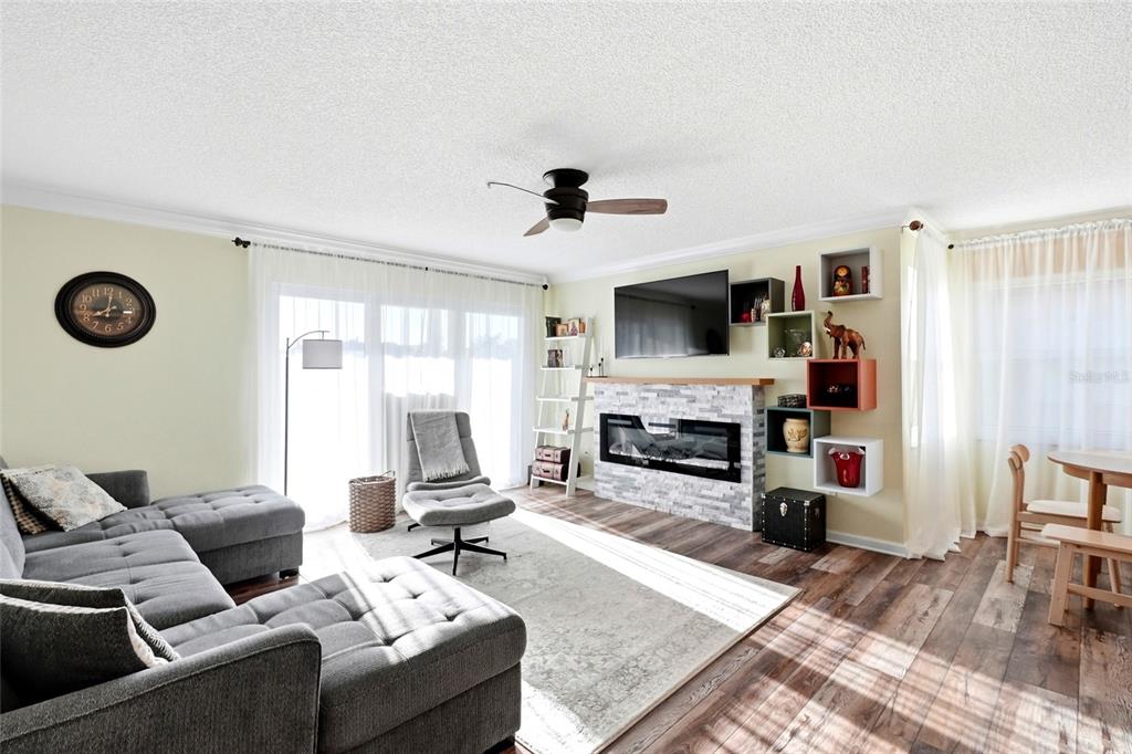 A living room features a grey sectional sofa, a fireplace with stone veneer, and shelving — 2400 FEATHER SOUND DRIVE UNIT 1428, CLEARWATER, FL