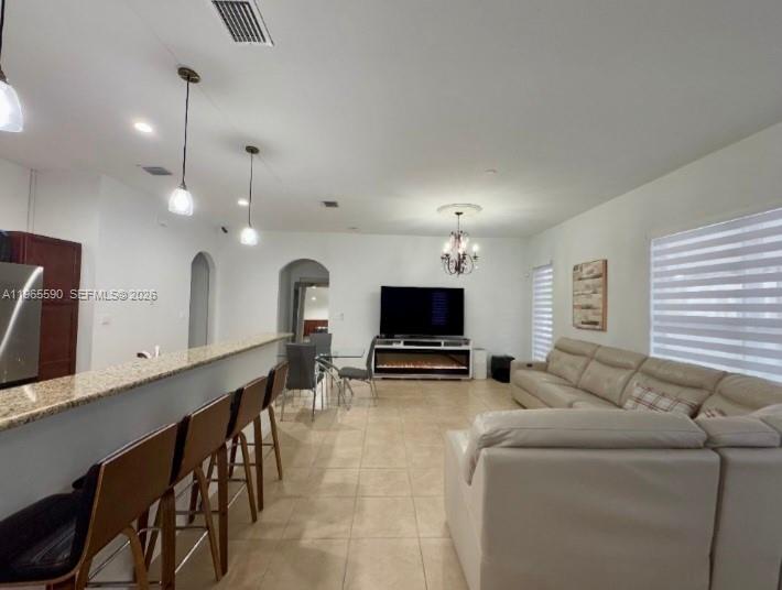 An open-concept living room features a kitchen island with bar stools and a large sofa — 17181 SW 91st St, Miami FL 33196, MIAMI, FL