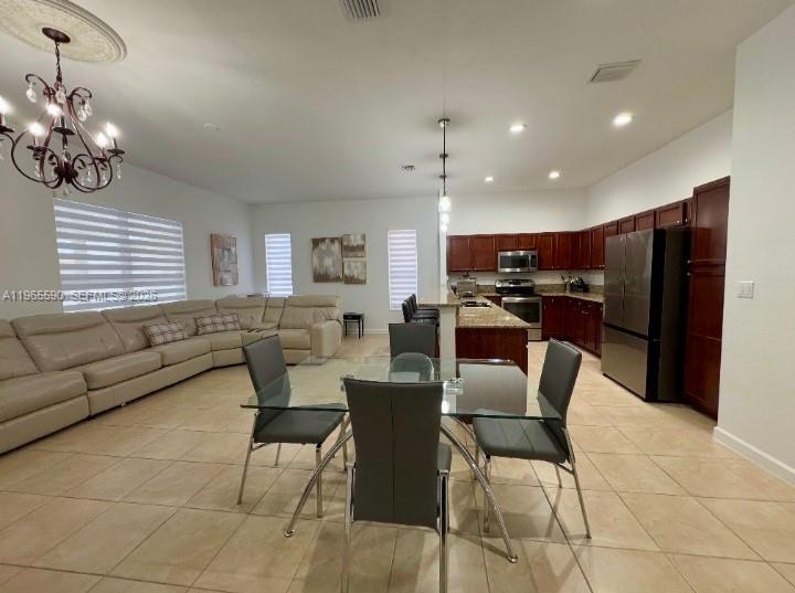 An open-concept living and dining area features a large sectional sofa and kitchen cabinetry — 17181 SW 91st St, Miami FL 33196, MIAMI, FL