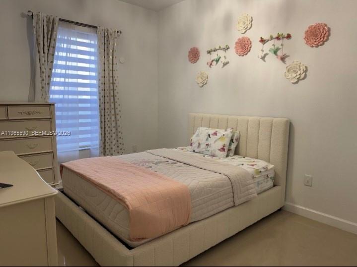 A bedroom features a bed with a light-colored headboard, a dresser, and wall-mounted floral decorations — 17181 SW 91st St, Miami FL 33196, MIAMI, FL