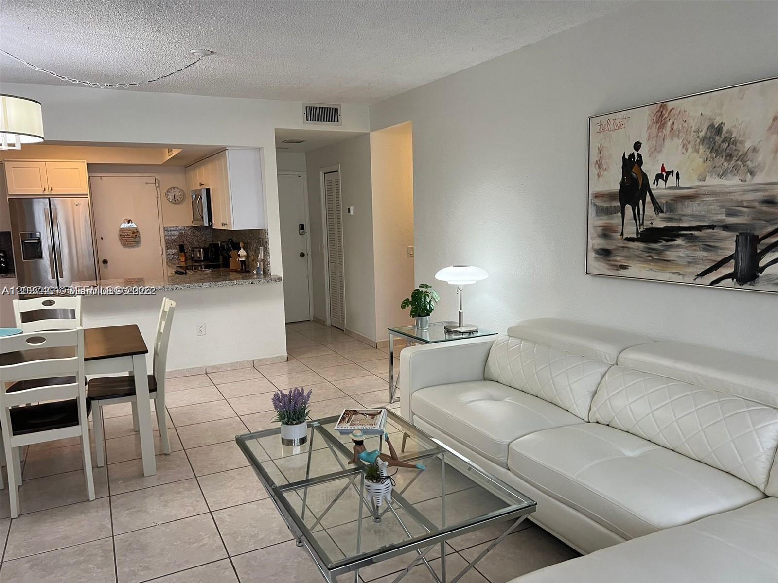 A living room with a white sofa, glass coffee table, and an adjacent kitchen area — 3505 S Ocean Dr # 208, Hollywood FL 33019, HOLLYWOOD, FL