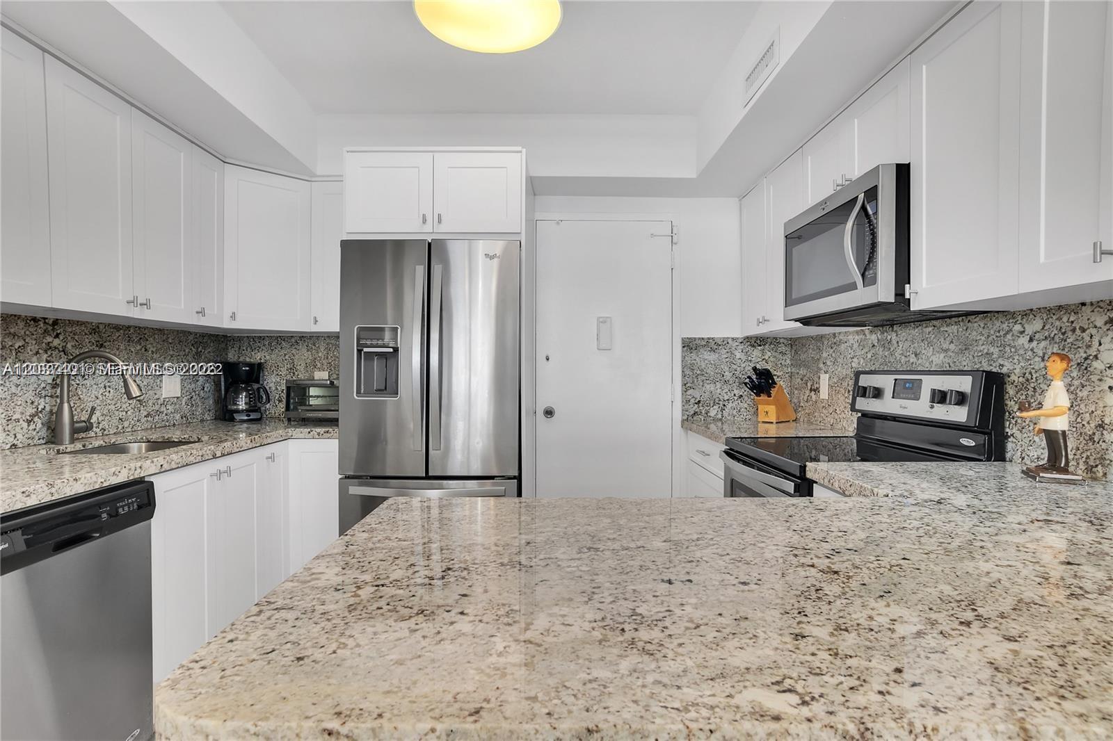 A kitchen features white cabinets, granite countertops, stainless steel appliances, and a central island — 3505 S Ocean Dr # 208, Hollywood FL 33019, HOLLYWOOD, FL