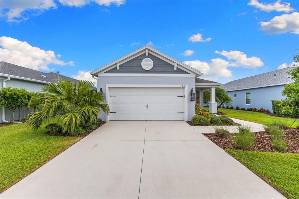 A single-story house with a white garage door, gray siding, and a concrete driveway — 13840 OLD CREEK COURT, PARRISH, FL