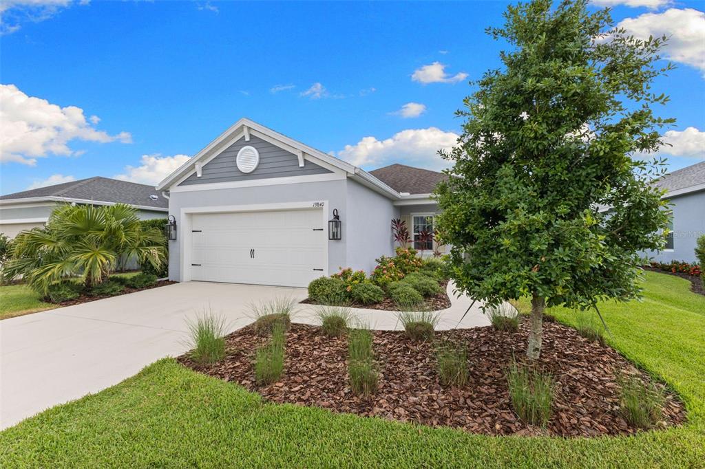 A single-story suburban house with a gray exterior, white garage door, and landscaped front yard — 13840 OLD CREEK COURT, PARRISH, FL