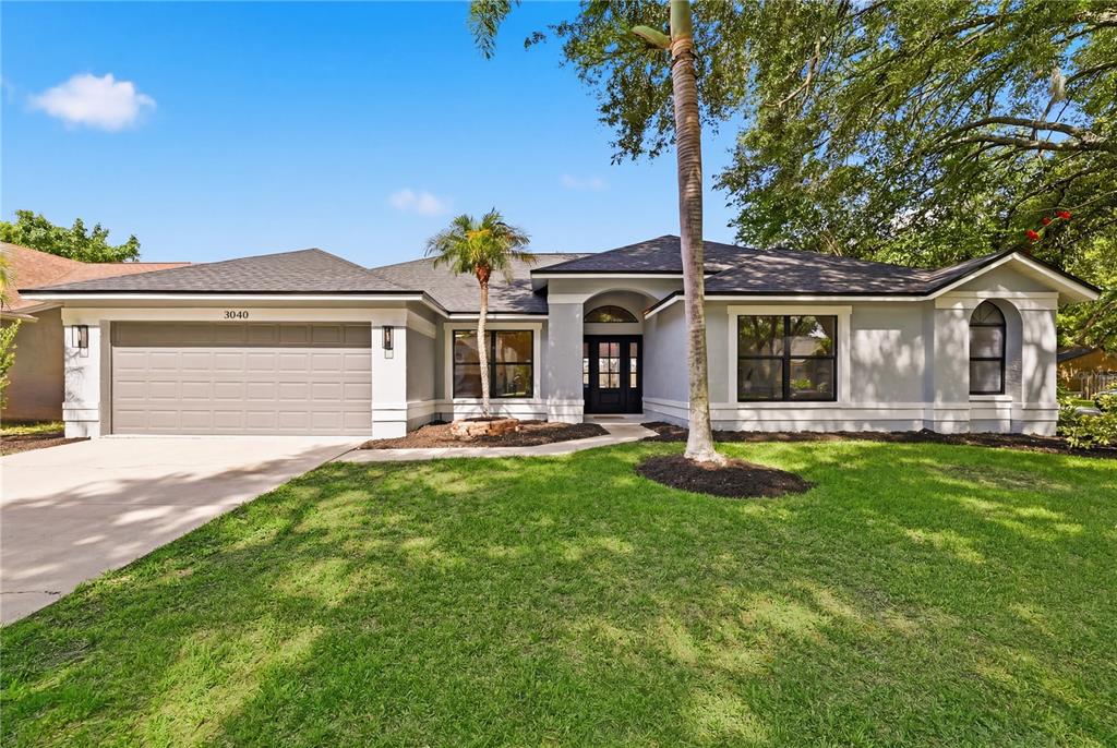 A single-story house with a gray exterior, a two-car garage, and a front lawn — 3040 WINDRIDGE OAKS DRIVE, PALM HARBOR, FL
