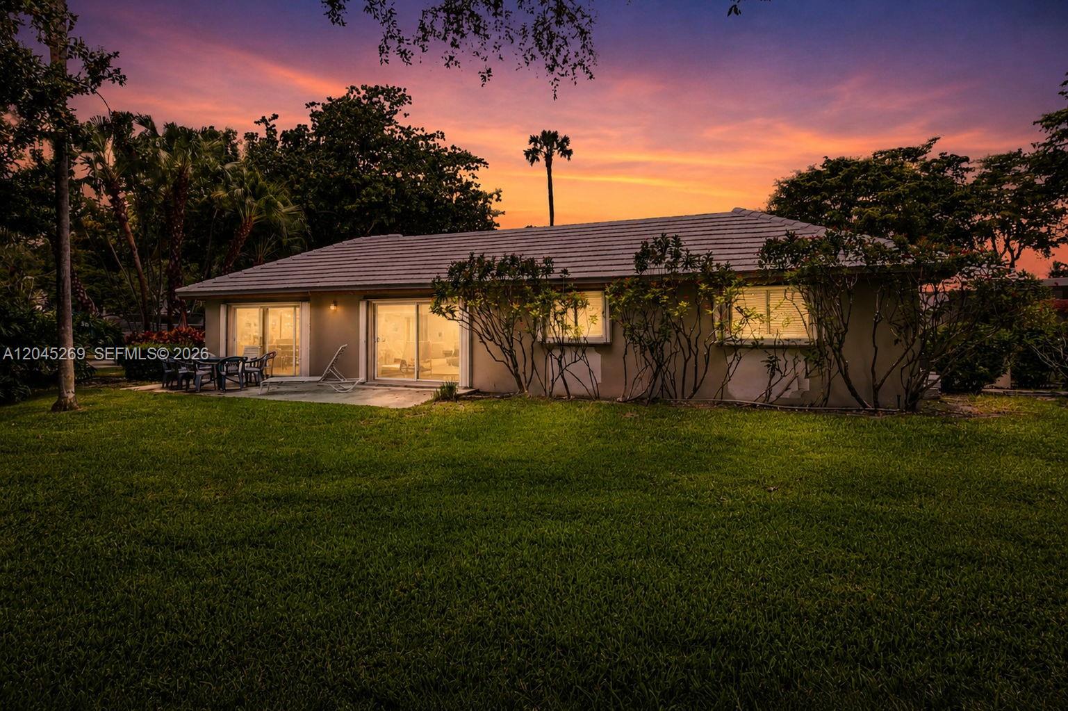 The exterior of a single-story house features a patio, sliding glass doors, and landscaping — 908 Cypress Ter # V57, Pompano Beach FL 33069, POMPANO BEACH, FL