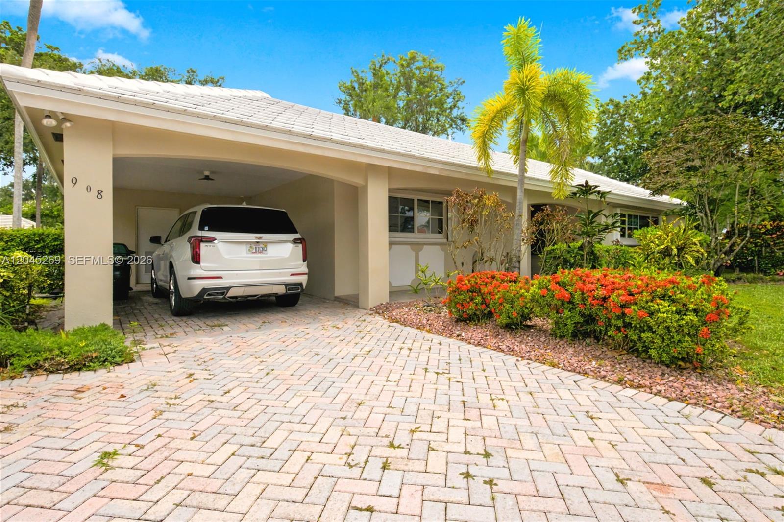 A single-story house with a white tiled roof, a paved driveway, and a covered carport — 908 Cypress Ter # V57, Pompano Beach FL 33069, POMPANO BEACH, FL