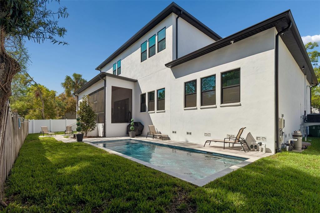 A modern three-car garage with dark doors and stone accents on a white exterior — 5410 BAYSHORE BLVD, TAMPA, FL