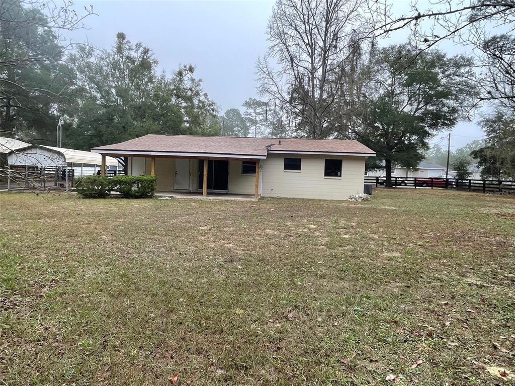 A single-story house with a covered patio and a large, grassy yard — 4486 SW 159TH COURT, OCALA, FL