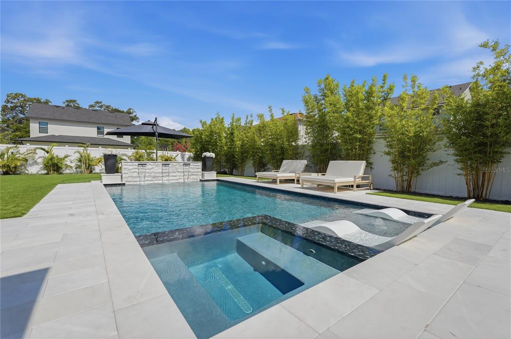 A backyard swimming pool with a built-in spa, water features, and lounge chairs on a patio — 4208 N CLEARFIELD AVENUE, TAMPA, FL