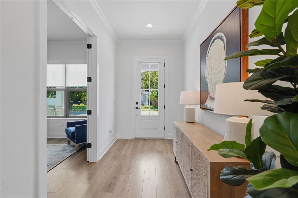 A bright entryway features light wood flooring, a white front door, and a wooden console table — 4208 N CLEARFIELD AVENUE, TAMPA, FL