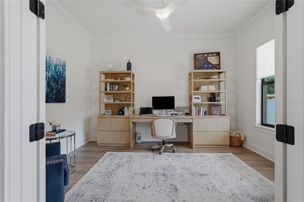 A home office features a built-in desk with shelving, a ceiling fan, and a rug — 4208 N CLEARFIELD AVENUE, TAMPA, FL