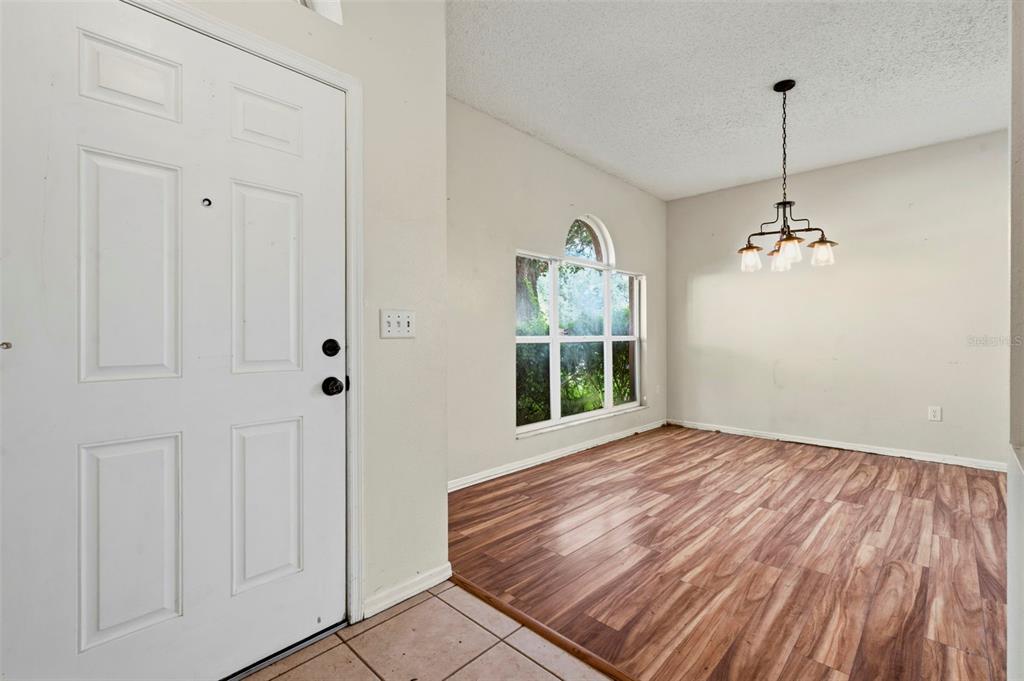 An entryway with tile flooring leads into a dining area featuring wood-look floors and chandelier — 507 GREG STREET, VALRICO, FL