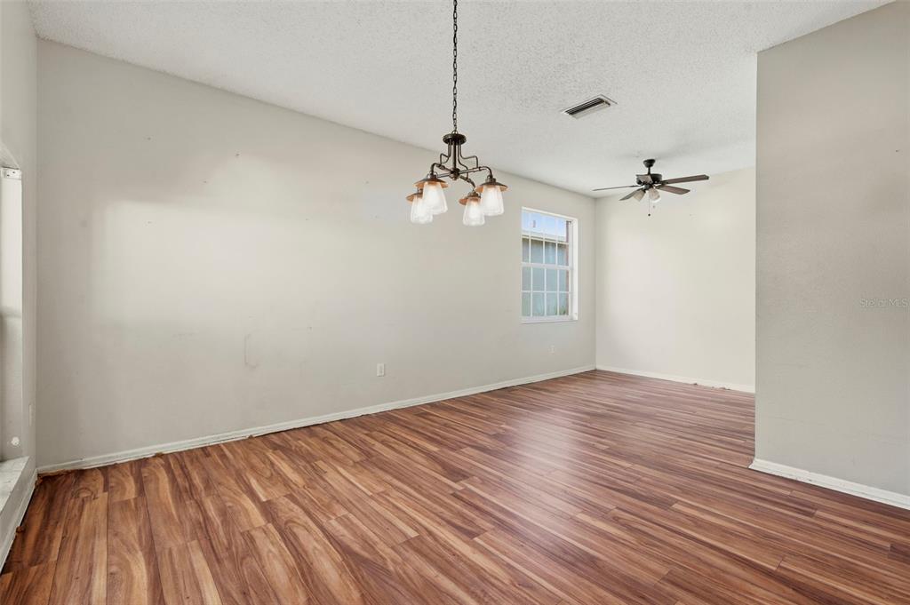 An empty dining room features wood-look flooring, a chandelier, and a ceiling fan — 507 GREG STREET, VALRICO, FL