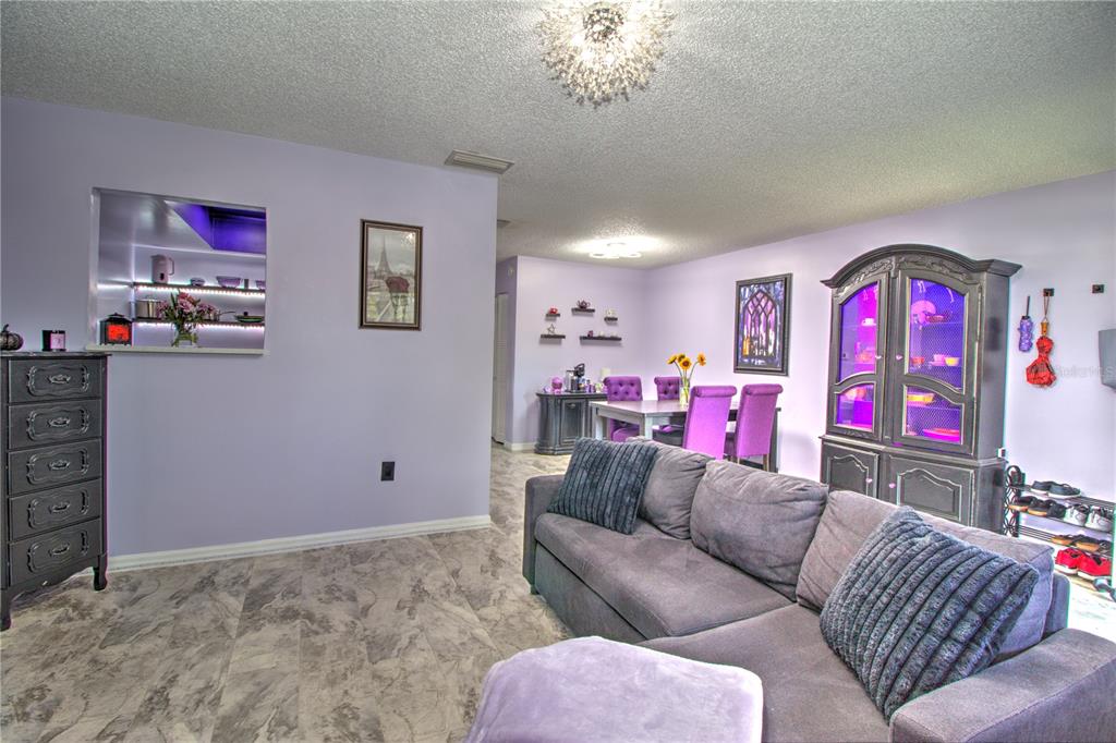 A living and dining area features light purple walls, gray marble-look flooring, and purple furniture — 1640 NE 40TH AVENUE UNIT 204, OCALA, FL