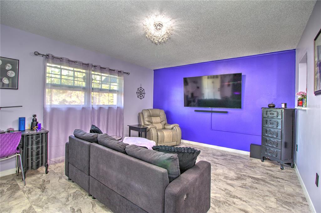 A living room features a purple accent wall, a gray sectional sofa, and tile flooring — 1640 NE 40TH AVENUE UNIT 204, OCALA, FL
