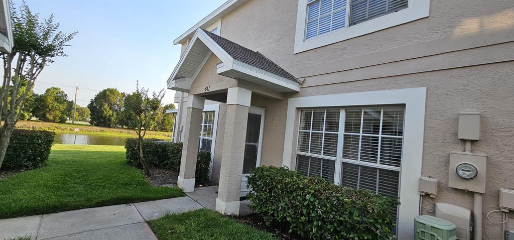 A beige two-story townhouse exterior features a covered entryway, white trim, and a small lawn — 641 KENSINGTON LAKE CIRCLE, BRANDON, FL