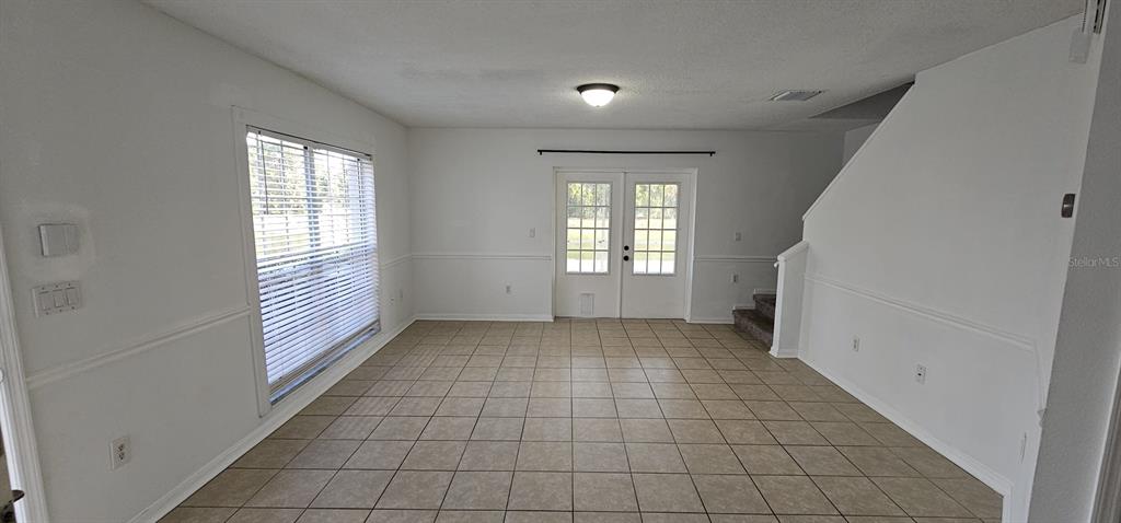An empty room features white walls, tile flooring, a window with blinds, and glass doors — 641 KENSINGTON LAKE CIRCLE, BRANDON, FL