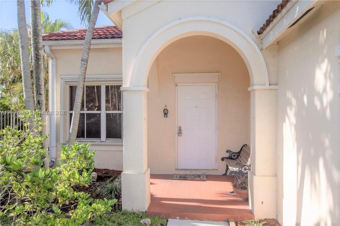 A covered entryway features a white front door, a tiled floor, and a small bench — 777 Tanglewood Cir, Weston FL 33327, WESTON, FL