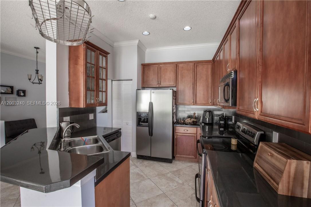 A kitchen features dark wood cabinets, black countertops, stainless steel appliances, and tile flooring — 777 Tanglewood Cir, Weston FL 33327, WESTON, FL