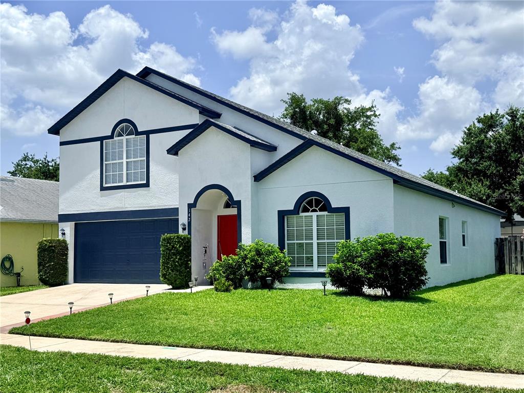 A two-story house with white stucco walls, blue trim, a red door, and a front lawn — 142 BRIGHTVIEW DRIVE, LAKE MARY, FL