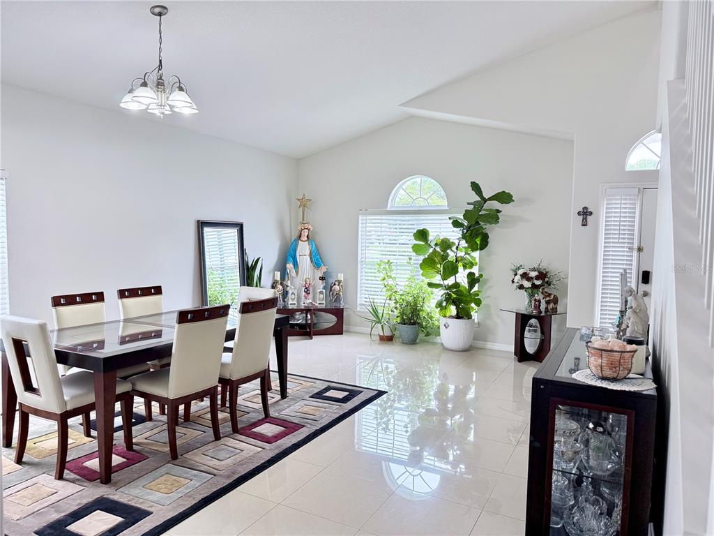 A dining room features a dark wood table, cream chairs, tile floors, and a large plant — 142 BRIGHTVIEW DRIVE, LAKE MARY, FL