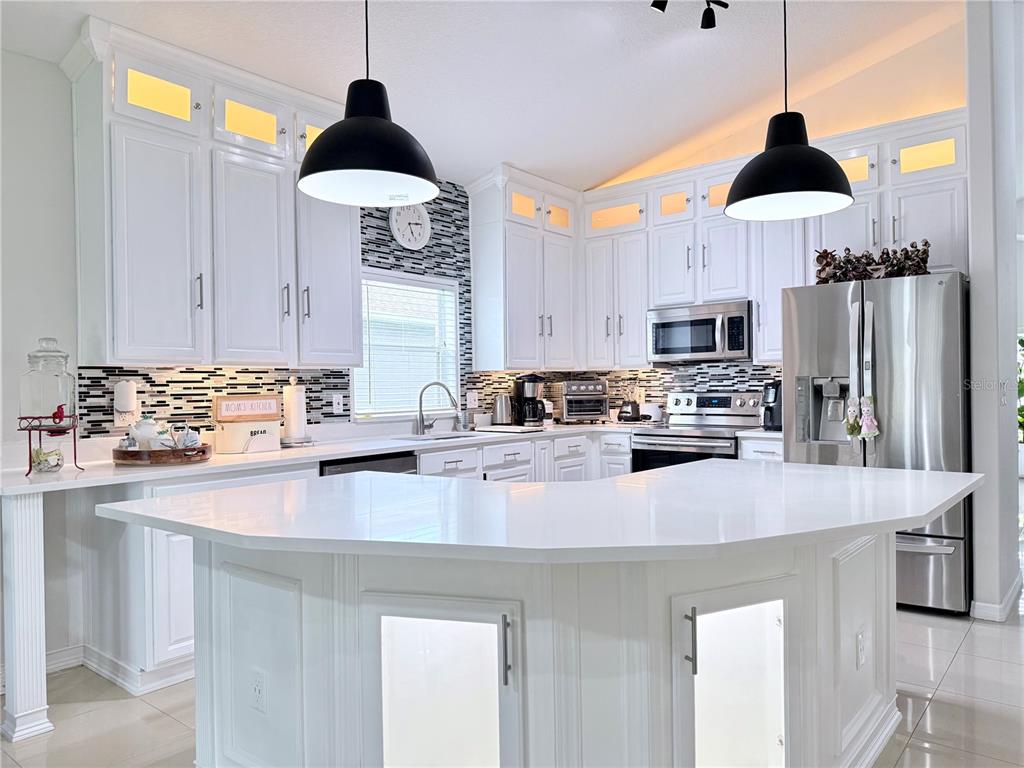 A bright kitchen features white cabinetry, a large central island, and a black-and-white tiled backsplash — 142 BRIGHTVIEW DRIVE, LAKE MARY, FL