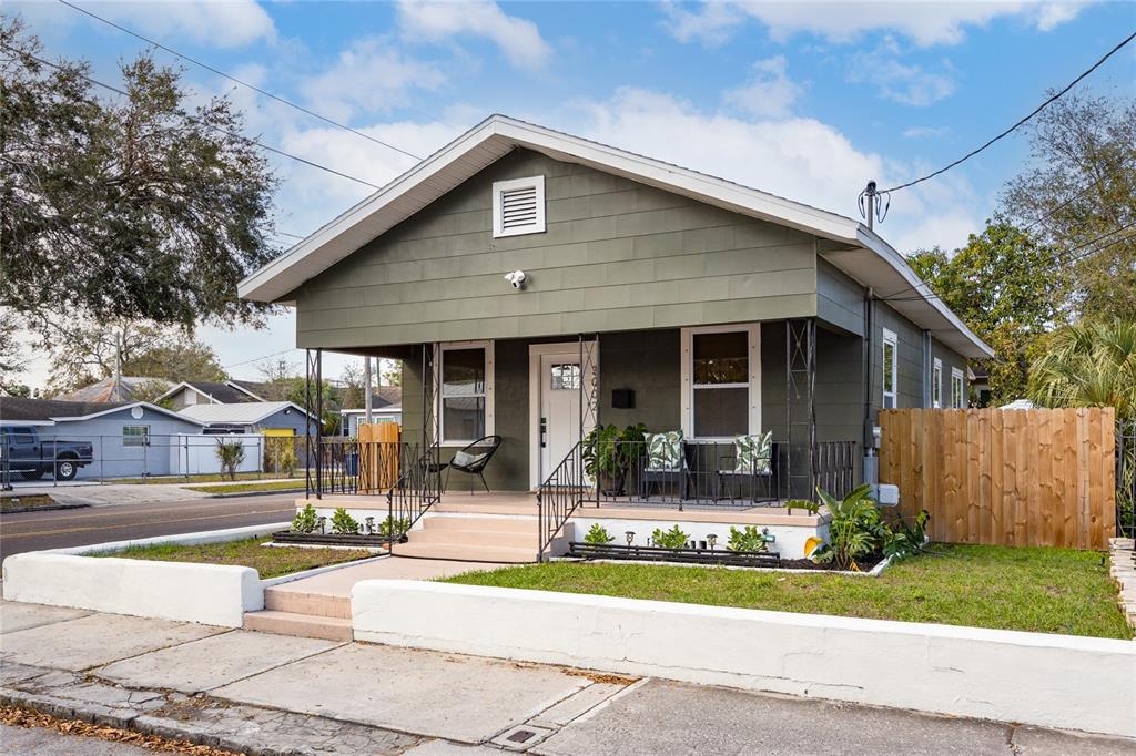 A single-story house with olive green siding, a front porch, and a low white wall — 3002 N 16TH STREET, TAMPA, FL