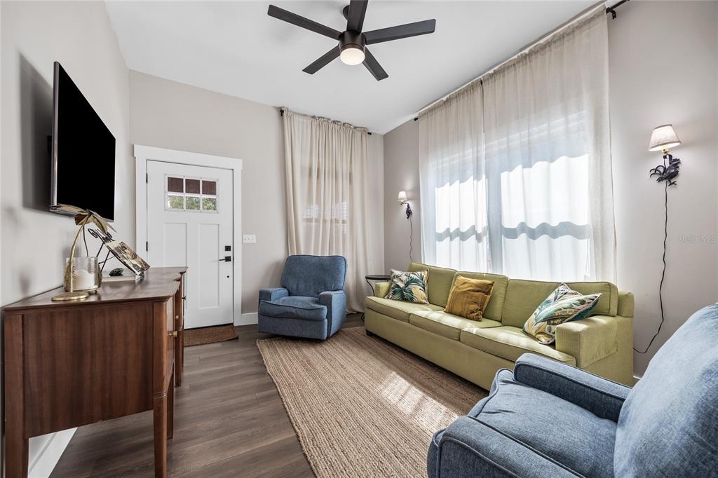 A living room features a green sofa, two blue armchairs, a television, and wood flooring — 3002 N 16TH STREET, TAMPA, FL