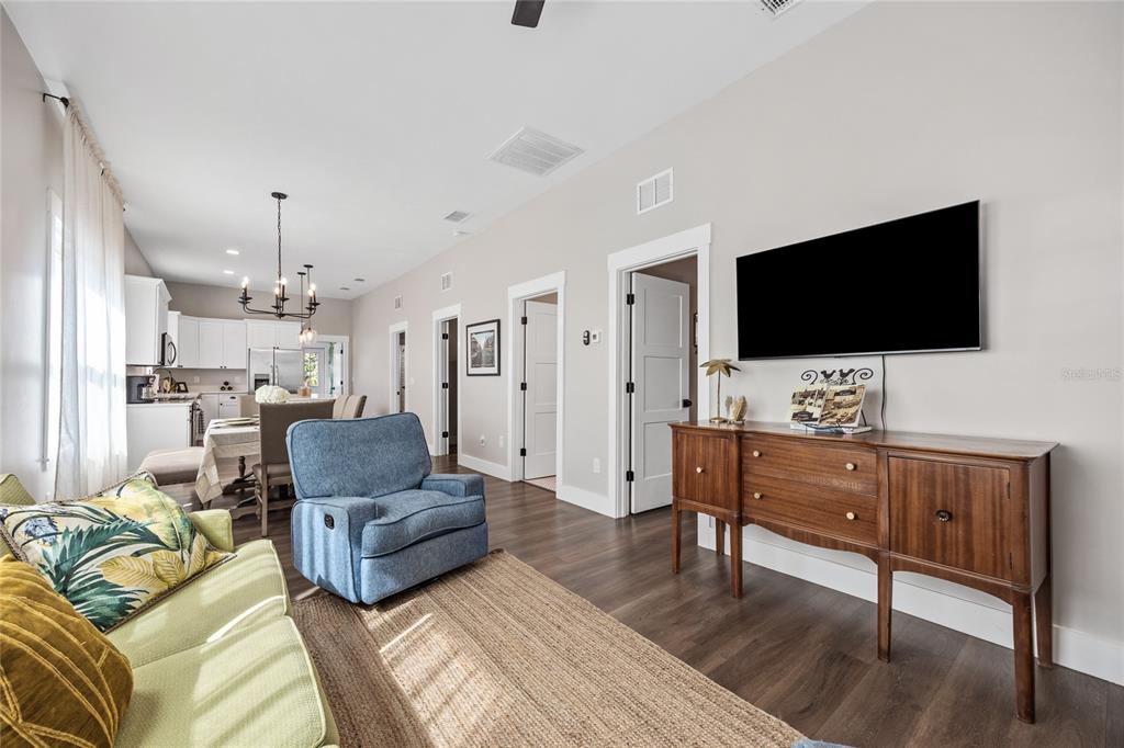 A living room with a blue recliner, green sofa, wood floors, and a wall-mounted television — 3002 N 16TH STREET, TAMPA, FL