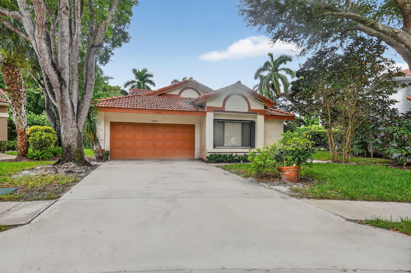 A single-story house with a terracotta tile roof, orange garage door, and concrete driveway — 20803 Cabrillo Way, Boca Raton FL 33428, BOCA RATON, FL