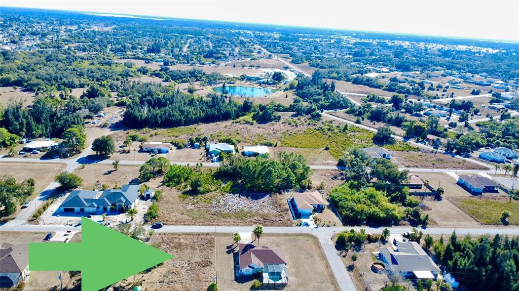 An aerial view shows a vacant residential lot with a large green arrow pointing toward it — LORANZA AVENUE, NORTH PORT, FL