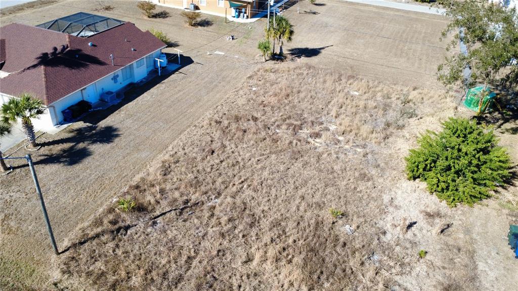 An aerial view shows a vacant, grass-covered residential lot next to a house with a pool — LORANZA AVENUE, NORTH PORT, FL