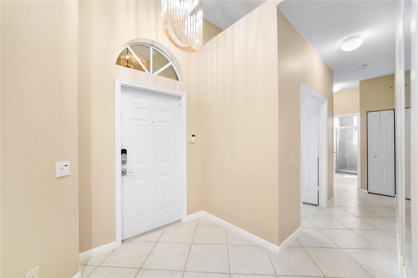 An entryway features a white front door with a transom window, tile flooring, and beige walls — 5021 S La Sedona Circle, Delray Beach FL 33484, DELRAY BEACH, FL