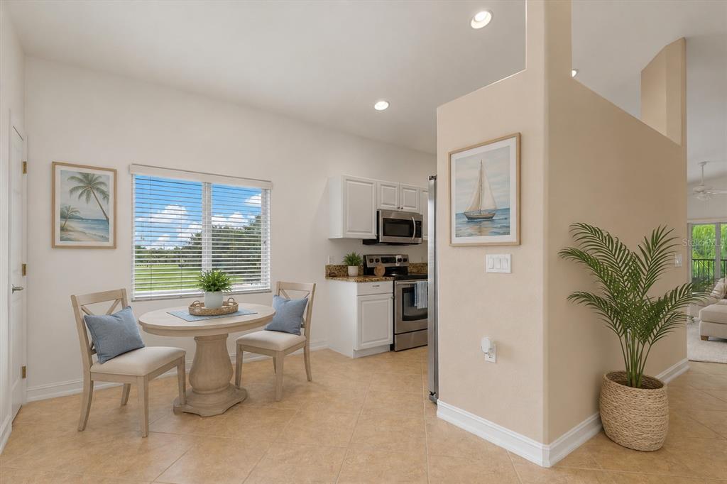 A dining area with a round table and chairs sits next to a small kitchen — 7196 N PLUM TREE UNIT 321, PUNTA GORDA, FL