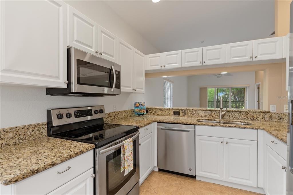 A kitchen features white cabinets, granite countertops, and stainless steel appliances — 7196 N PLUM TREE UNIT 321, PUNTA GORDA, FL