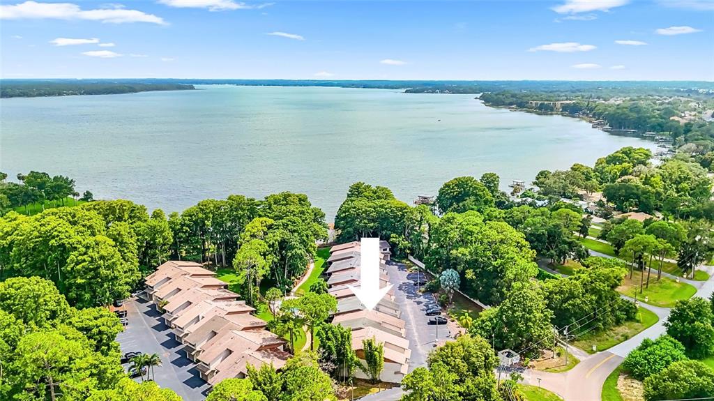 An aerial view shows a multi-unit townhouse complex situated near a large lake — 2122 TARPON LANDINGS DRIVE, TARPON SPRINGS, FL