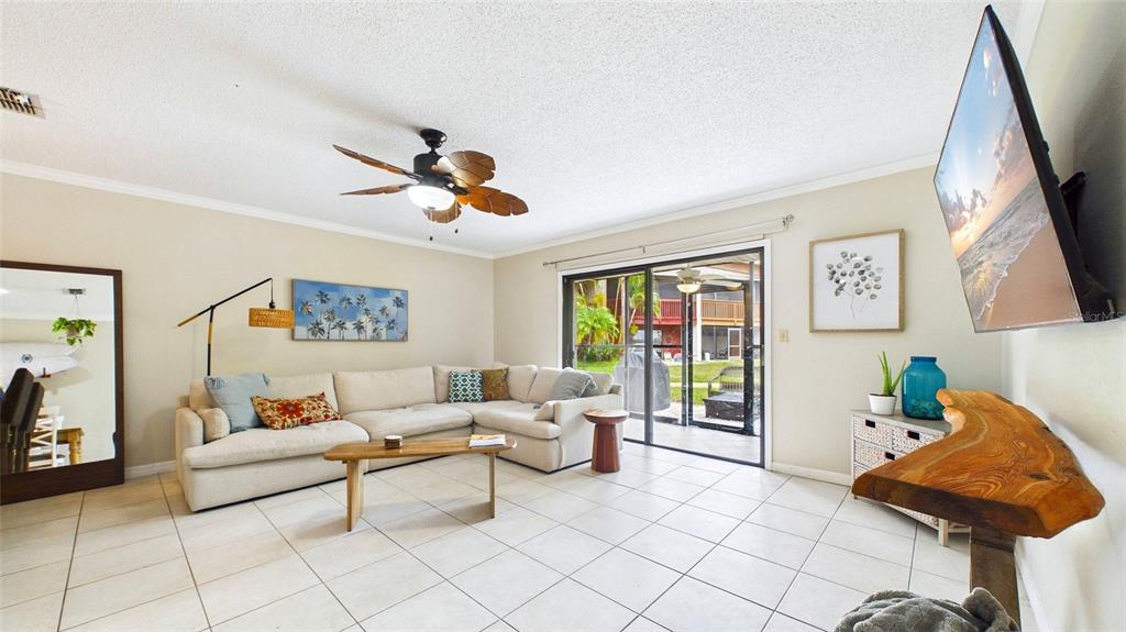 A living room features a sectional sofa, tile flooring, a ceiling fan, and a television — 2122 TARPON LANDINGS DRIVE, TARPON SPRINGS, FL