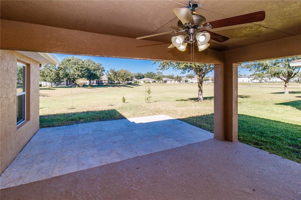 A covered patio features a ceiling fan, tiled flooring, and a view of a grassy yard — 13541 NITI DRIVE, HUDSON, FL