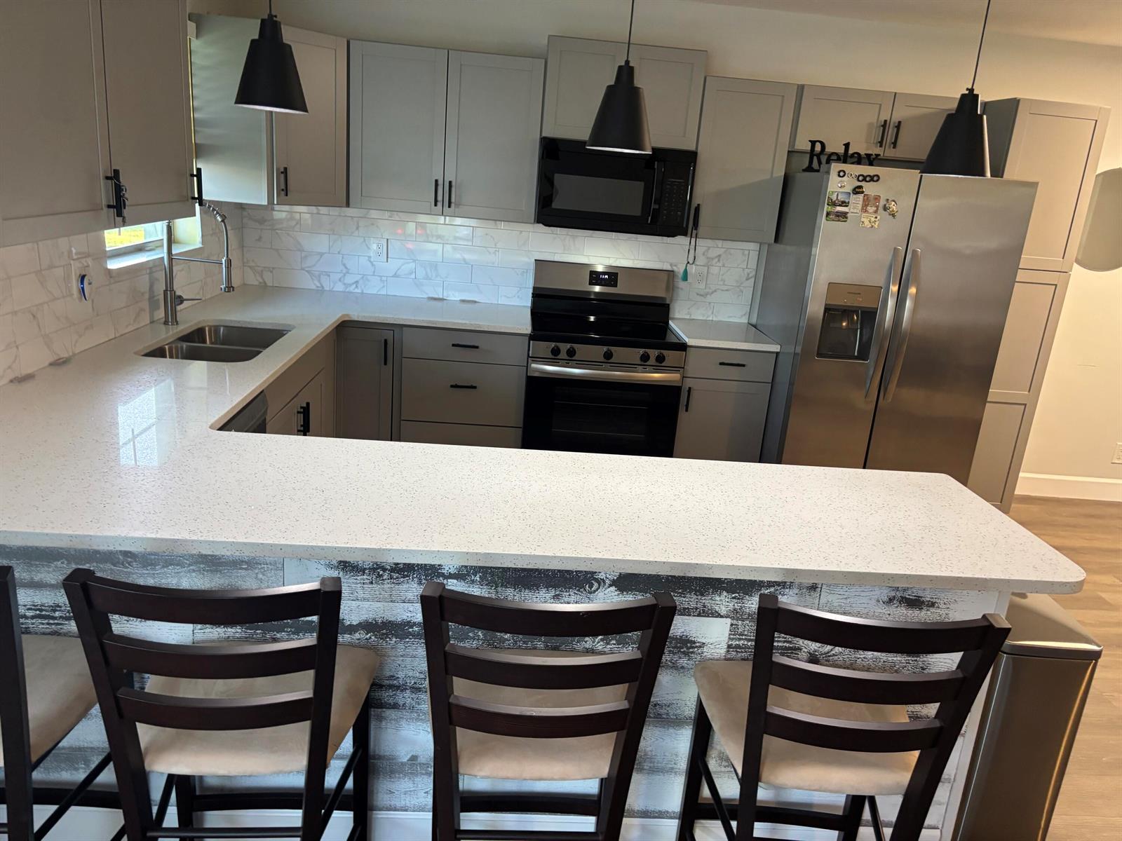 A kitchen with gray cabinets, white speckled countertops, stainless steel appliances, and a breakfast bar — 211 Country Lane # C, Boynton Beach FL 33435, BOYNTON BEACH, FL