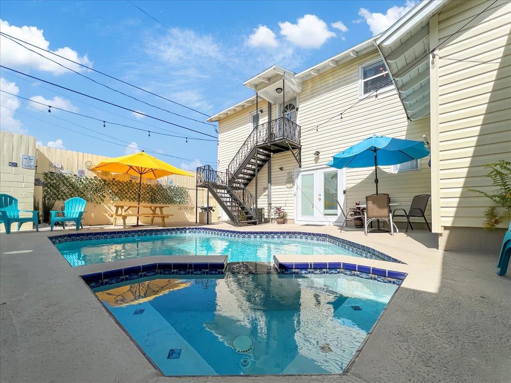 A backyard features a swimming pool, a hot tub, a metal staircase, and patio furniture — 3801 1ST AVENUE S, ST PETERSBURG, FL