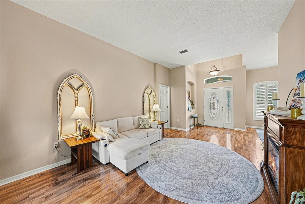 A living room features a sectional sofa, two arched wall mirrors, and wood-look flooring — 12251 CREEK EDGE DRIVE, RIVERVIEW, FL